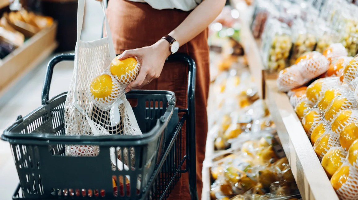 a person placing grapefruits in a shopping basket